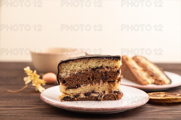 Chocolate biscuit cake with caramel cream, cup of coffee on brown wooden background. side view, close up, selective focus, copy space