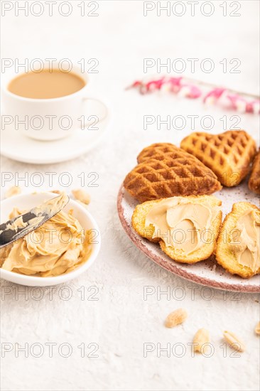 Homemade waffle with peanut butter and cup of coffee on a gray concrete background. side view, close up, selective focus