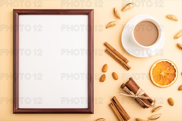 Composition with wooden frame, almonds, cinnamon and cup of coffee. mockup on orange background. Blank, flat lay, top view, still life, copy space