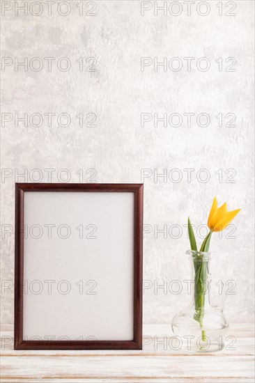 Wooden frame with orange tulip flower in glass on gray concrete background. side view, copy space, still life, mockup, template, spring, summer minimalism concept