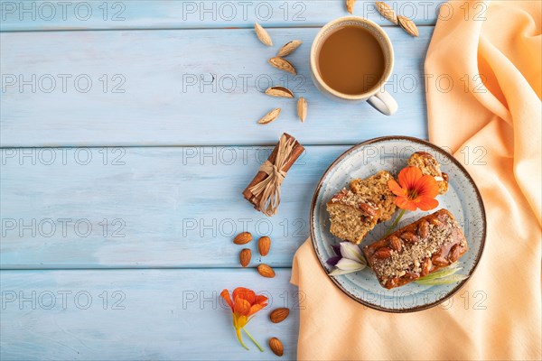 Caramel and almond cake with cup of coffee on blue wooden background and orange linen textile. top view, flat lay, copy space