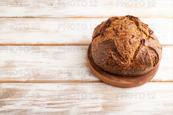 Fresh homemade golden grain bread with wheat and rye on white wooden background. side view, copy space