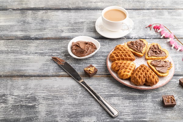 Homemade waffle with chocolate butter and cup of coffee on a gray wooden background. side view, copy space