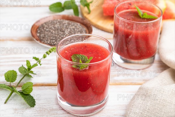 Watermelon juice with chia seeds and mint in glass on a white wooden background with linen textile. Healthy drink concept. Side view, close up