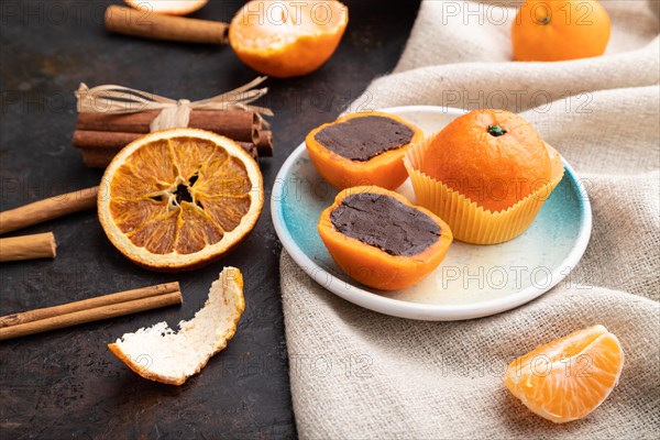 Truffle chocolate tangerine candies on a black concrete background and linen textile. Side view, close up