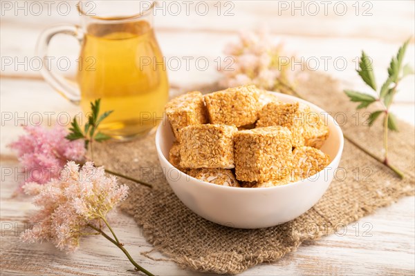 Traditional turkish delight (rahat lokum) in white ceramic plate with glass of green tea on a white wooden background. side view, close up, selective focus