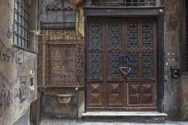 18th century Madonna and Child, protected by a wrought-iron grille, on the right an old barred entrance door in the historic centre, Al civ. 11 r. di Vico cinque Lampadi, Genoa, Italy, Europe