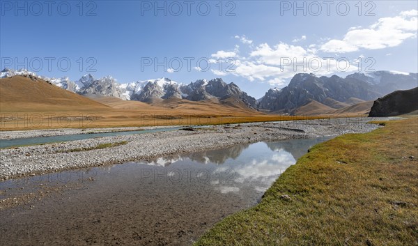 Reflection in the river Kol Suu, hiking trail to the mountain lake Kol Suu, mountain landscape with yellow meadows and mountain peaks with glaciers, Keltan Mountains, Sary Beles Mountains, Tien Shan, Naryn Province, Kyrgyzstan, Asia