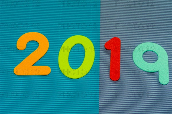 The numbers 2019 made of felt of different colors photographed on blue and maroon corrugated background