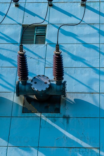 High voltage power lines with ceramic insulators on side of power transfer station building