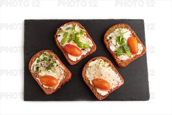Red beet bread sandwiches with cream cheese, tomatoes and microgreen on black board isolated on white background. top view, flat lay, close up