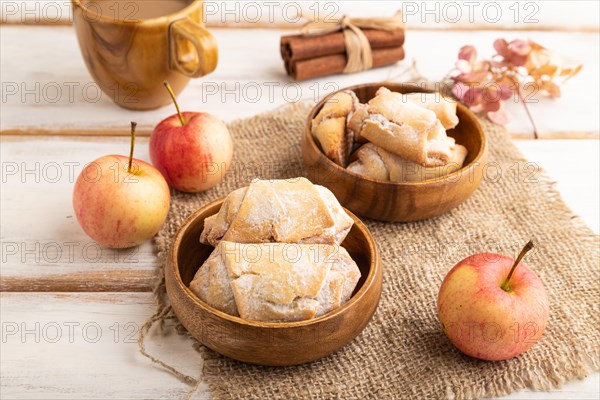 Homemade sweet cookie with apple jam and cup of coffee on white wooden background and linen textile. side view, close up