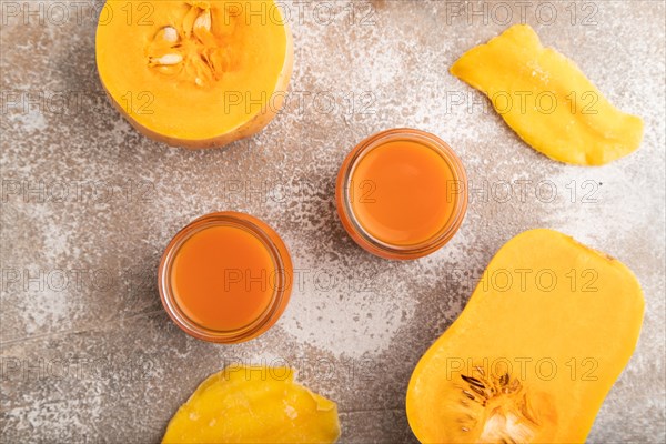 Baby puree with fruits mix, pumpkin, persimmon, mango infant formula in glass jar on brown concrete background. Top view, flat lay, close up, artificial feeding concept