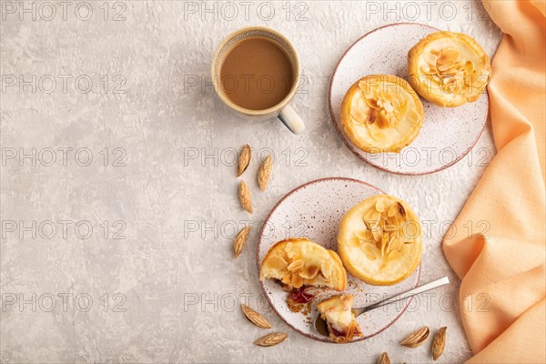 Traditional portuguese cakes pasteis de nata, custard small pies with almonds with cup of coffee on gray concrete background and orange textile. Top view, flat lay, copy space
