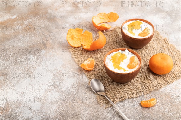 Grained cottage cheese with tangerine jam on brown concrete background and linen textile. side view, copy space