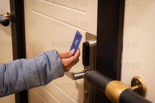 Close-up of a hand holding a key card to unlock a hotel door