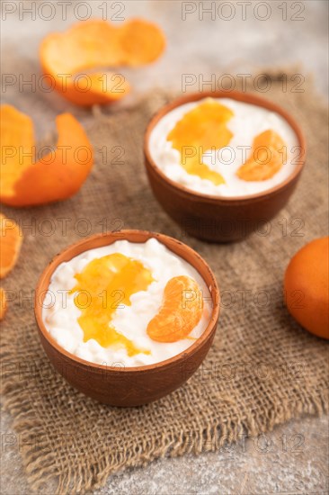 Grained cottage cheese with tangerine jam on brown concrete background and linen textile. side view, close up, selective focus