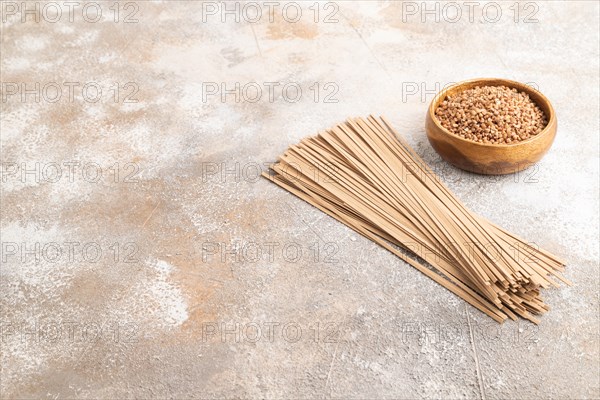 Japanese buckwheat soba noodles with tomato, eggs, spices, herbs on brown concrete background. Side view, copy space