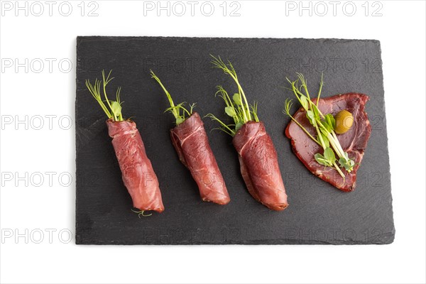 Slices of smoked salted meat with green pea microgreen isolated on white background. Top view, flat lay, close up