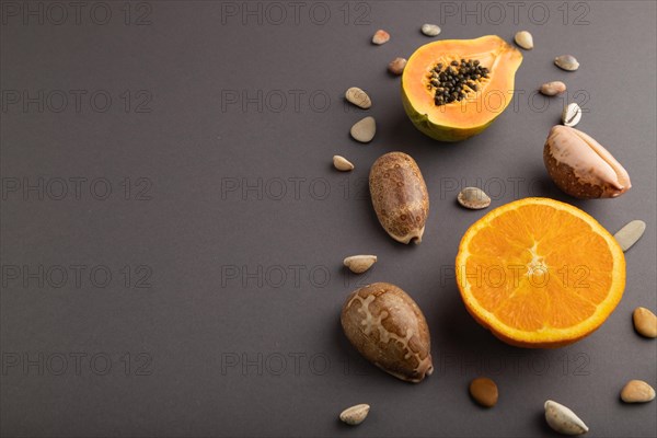 Ripe cut papaya, orange, seashells on gray pastel background. Side view, copy space. Tropical, healthy food, vacation, holidays concept, minimalism
