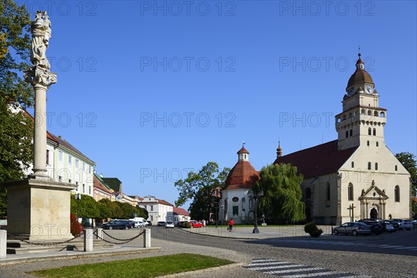 Town square with a statue in the foreground, church in the background on a sunny day, Roman Catholic parish church of St Michael, Marian column on the left, Skalica, Skalica, Trnavsky kraj, Slovakia, Europe