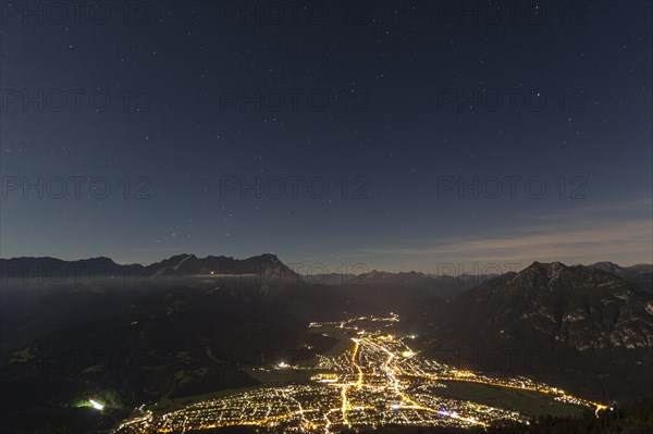 Night shot of an illuminated town in front of mountains, starry sky, Garmisch-Partenkirchen, Zugspitze on the left, Kramer on the right, Bavarian Alps, Upper Bavaria, Bavaria, Germany, Europe