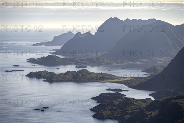 View of the coast in Ulvagsundet fjord and mountains in the evening light, Hurtigruten cruise ship in the fjord, view from the summit of Dronningsvarden or Stortinden, Vesteralen, Norway, Europe