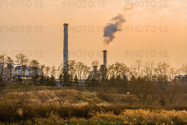 Large column of smoke rising from tall white smokestack in rural community in South Korea