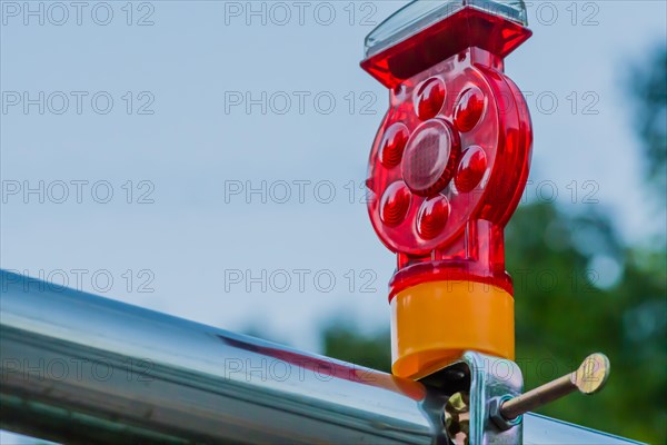Closeup of red warning reflector with yellow base attached to chrome support rod
