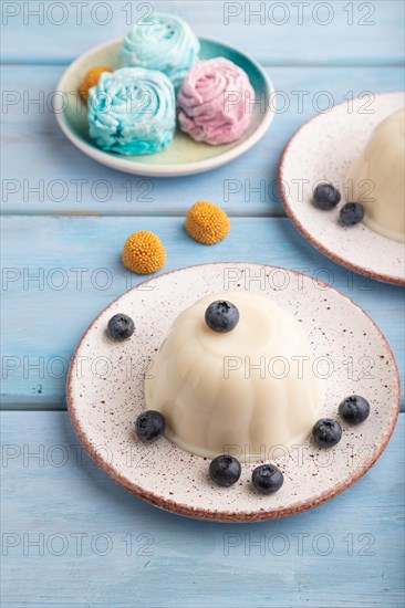 White milk jelly with blueberry on blue wooden background and blue linen textile. side view, close up
