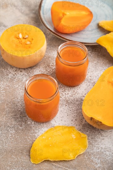 Baby puree with fruits mix, pumpkin, persimmon, mango infant formula in glass jar on brown concrete background. Side view, close up, artificial feeding concept