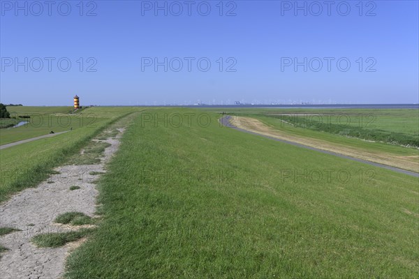 Dyke with Pilsum lighthouse and view of Eemshaven, Krummhoern, Germany, Europe