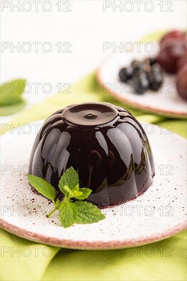 Black currant and grapes jelly on gray concrete background and green linen textile. side view, close up, selective focus