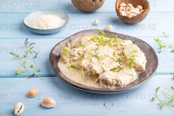 Stewed chicken fillets with coconut milk sauce and mizuna cabbage microgreen on blue wooden background. side view, close up