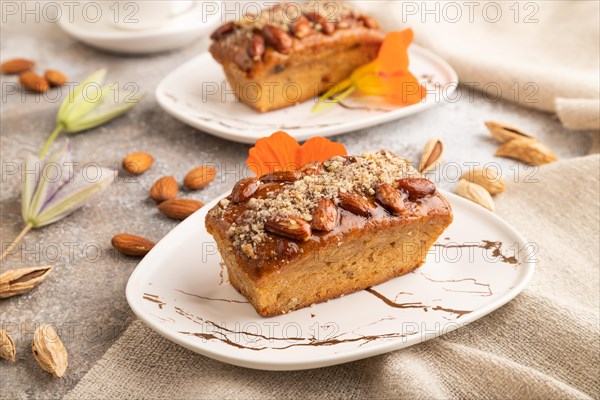 Caramel and almond cake with cup of coffee on brown concrete background and linen textile. side view, close up