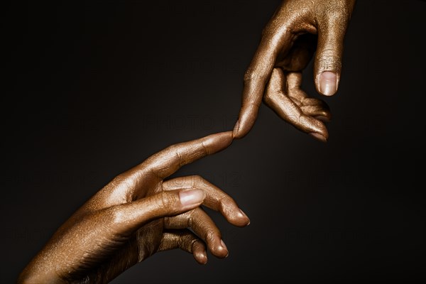 Beautiful man's hands in golden paint on black background close up