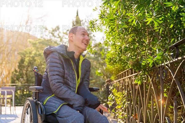 Low angle view portrait of a happy disabled man contemplating nature in an urban park in a sunny day
