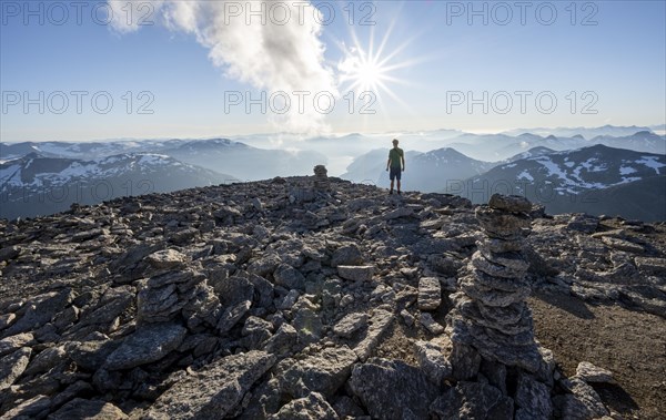 Mountaineer on the summit of Skala with cairn, view of mountain landscape and fjord Faleidfjorden, Sonnenstern, Loen, Norway, Europe