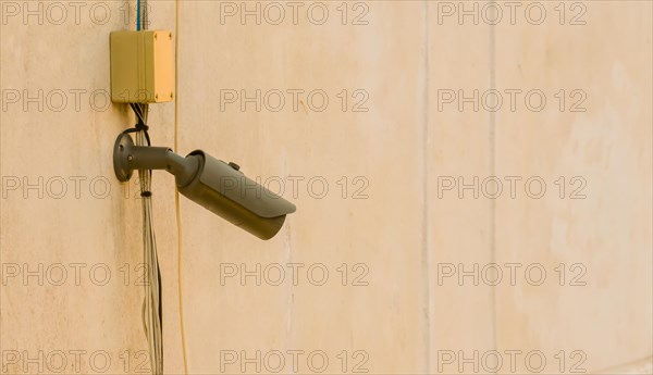 CCTV security camera and associated wires mounted under window on side of dirty concrete building