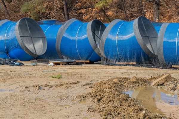 Large blue sections of steel industrial pipes sitting at construction site