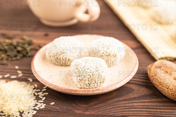 Japanese rice sweet buns mochi filled with pandan and coconut jam and cup of green tea on brown wooden background. side view, close up, selective focus