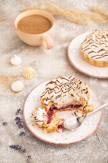 Two tartlets with meringue cream and cup of coffee on brown concrete background. side view, selective focus. Breakfast, morning, concept