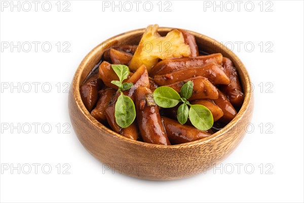 Tteokbokki or Topokki, fried rice cake stick, popular Korean street food with spicy jjajang sauce and pineapple isolated on white background. Side view