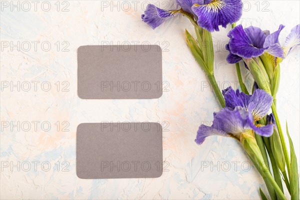 Gray business card with blue iris flowers on white concrete background. top view, flat lay, copy space, still life. Breakfast, morning, spring concept