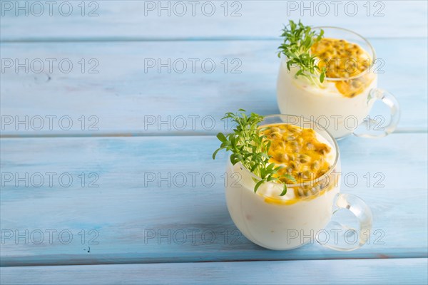 Mango yogurt with passionfruit and cilantro microgreen in glass on blue wooden background. Side view, copy space