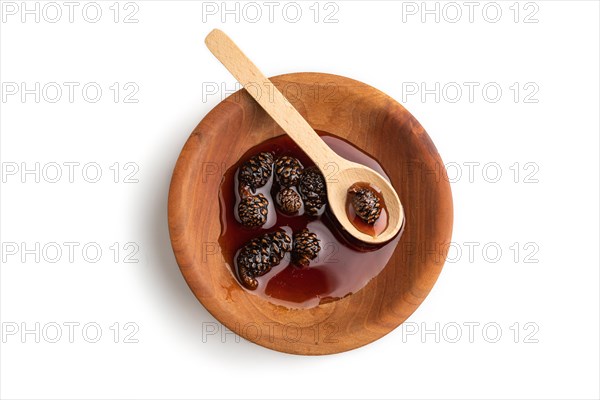 Pine cone jam in wooden bowl isolated on white background. Top view, flat lay, close up