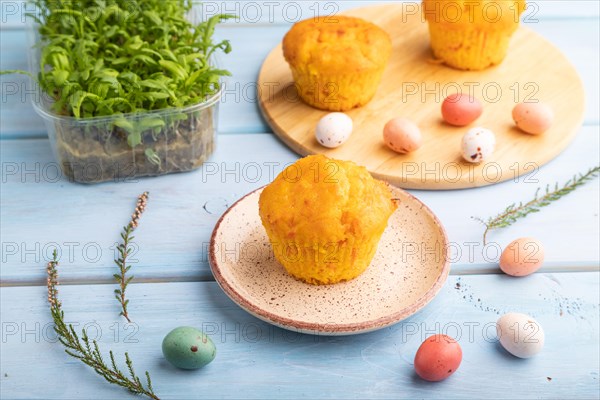 Homemade cakes with chocolate eggs and chrysanthemum microgreen on a blue wooden background. side view, close up