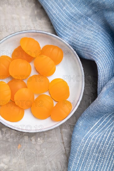 Jelly pumpkin candies on gray concrete background and blue linen textile. close up, top view, flat lay. autumn concept