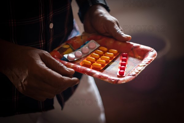 Man holding a bowl of pills, rural health centre, Tamil Nadu, India, Asia