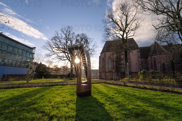 Sculpture with translucent sunbeams in front of a church and a clear sky, Pforzheim, Germany, Europe